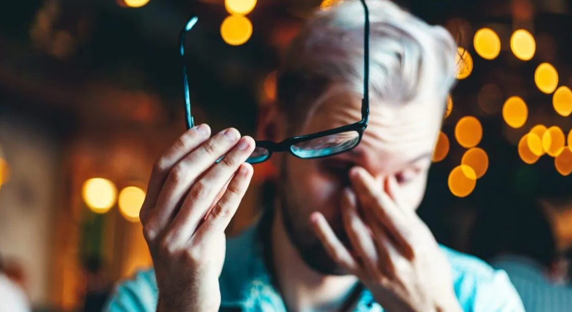 man holding his glasses and his bridge nose